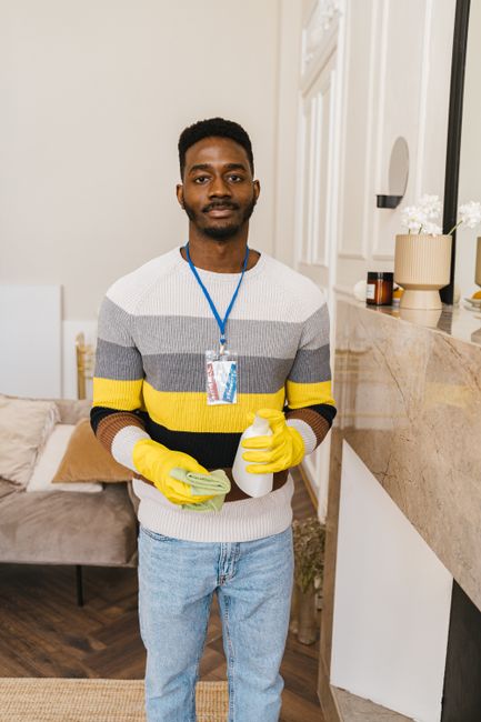 Three professional cleaners from West Kensington Cleaners are performing surface cleaning and deep cleaning tasks in a modern kitchen. The scene features a clean, minimalist space with a large marble 
